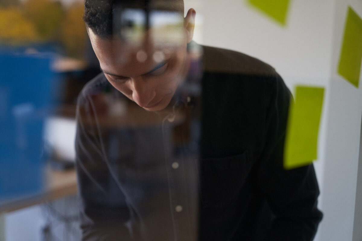 En man står bakom en glasvägg med postit-lappar