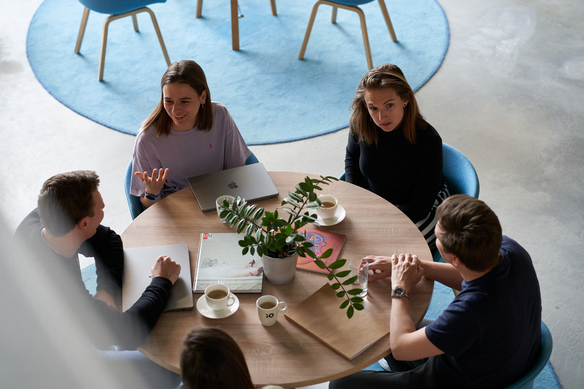 Två kvinnor och två män sitter vid ett runt bord och diskuterar