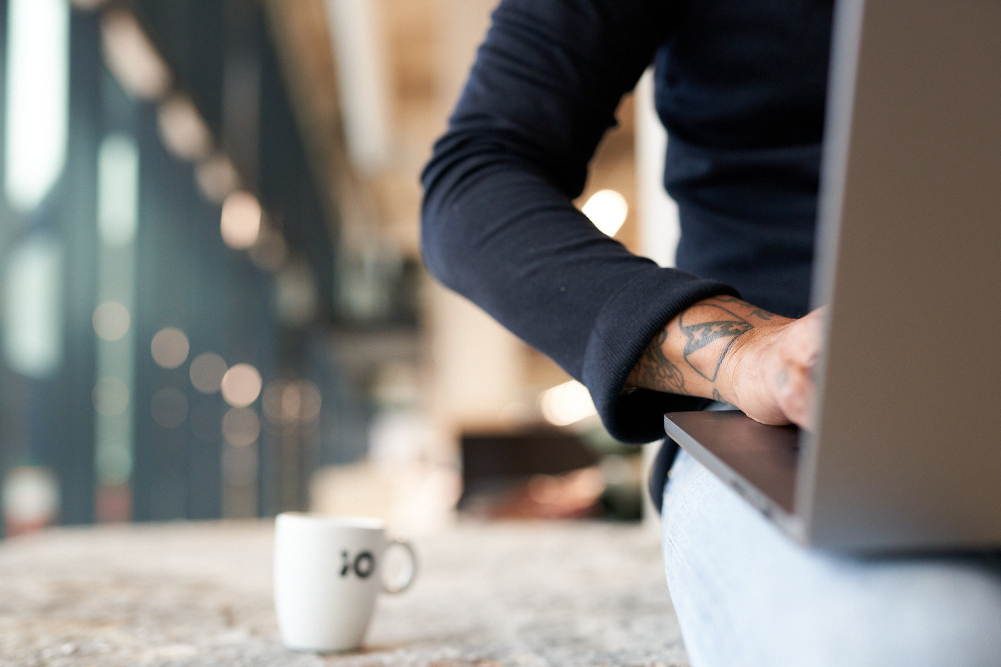 Närbild av en tatuerad arm som skriver på en laptop