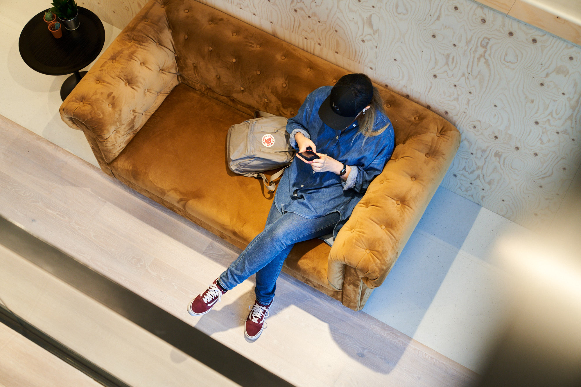 Kvinna sitter i en soffa och tittar i sin mobiltelefon